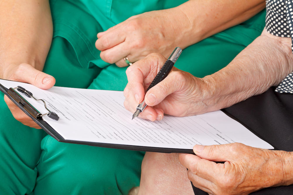 A senior woman's hand signing a document