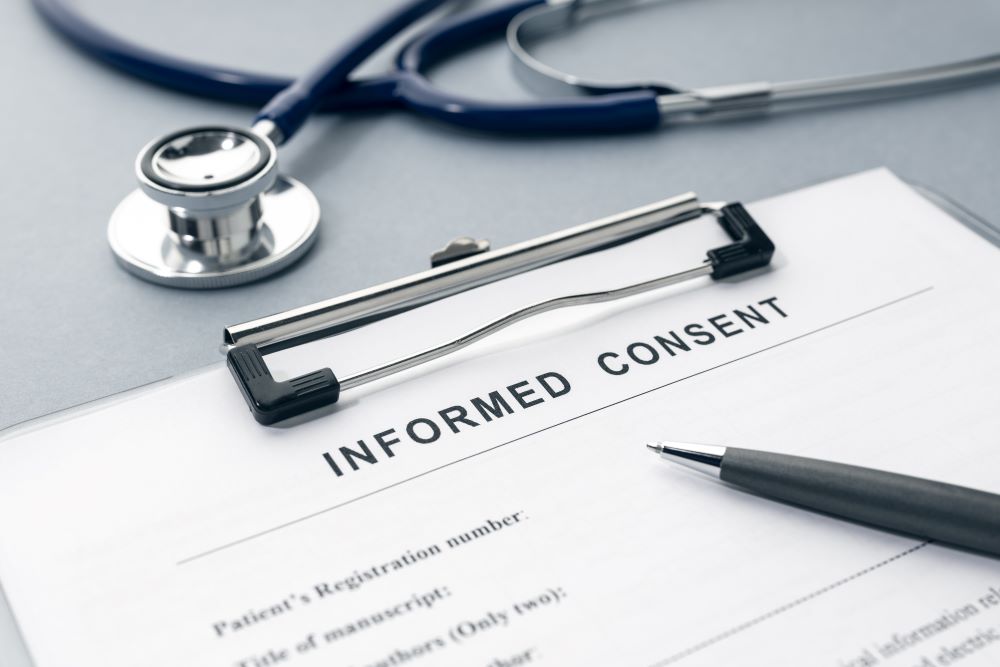 An informed consent patient form on a desk with a stethoscope next to it.