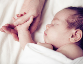 Baby holding an adult's thumb