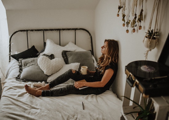 Woman sitting on bed contemplating her assault 