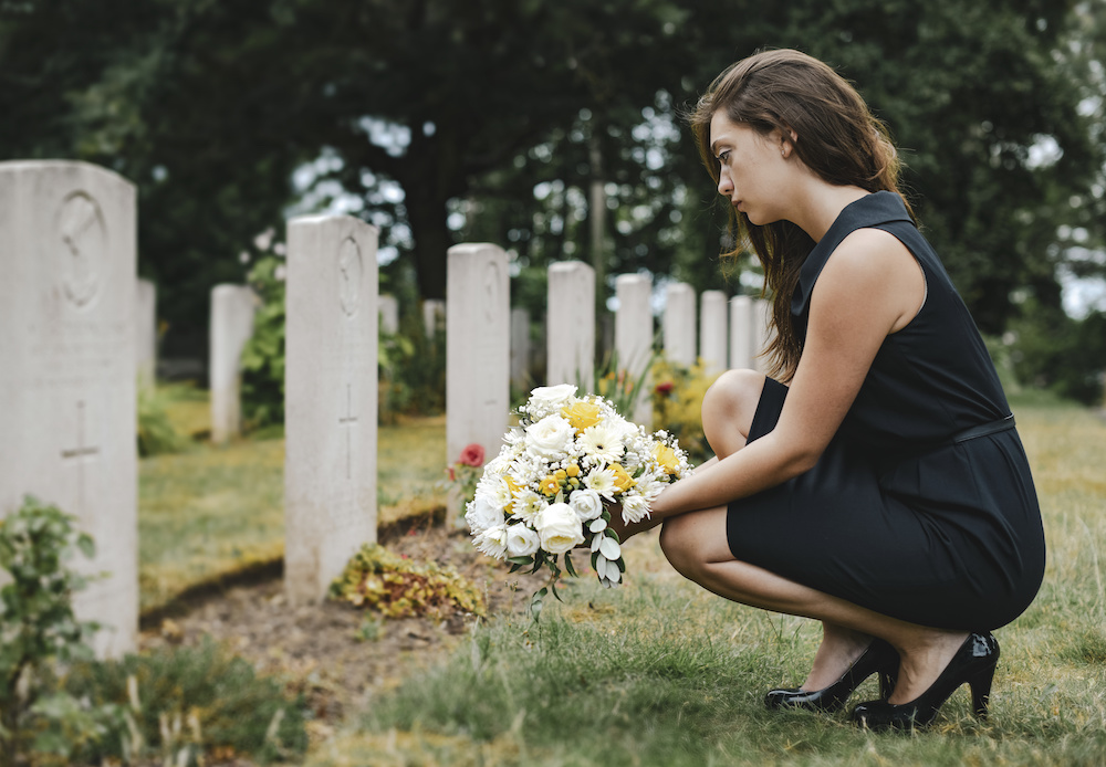 widow visiting her husband's grave after filing a wrongful death claim with a wrongful death lawyer